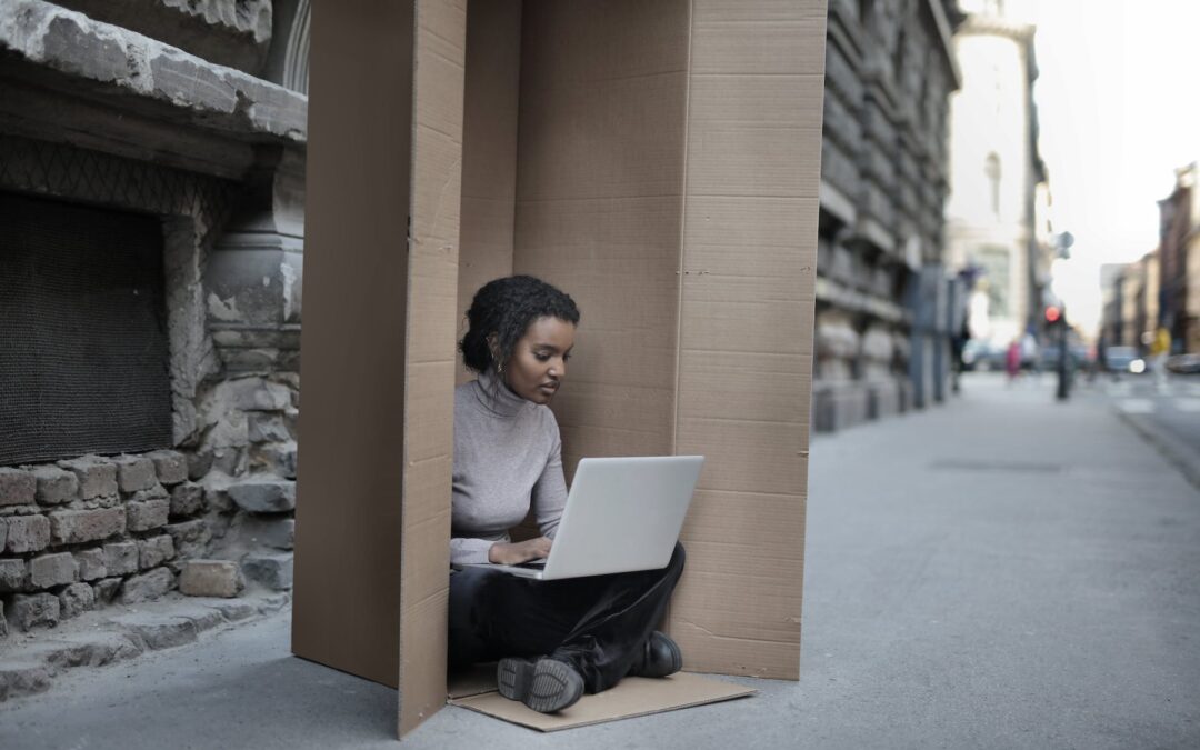 african american female sitting inside cardboard box with laptop