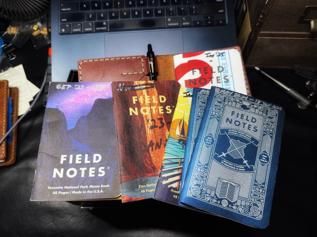 a collection of field notes notebooks on a cluttered desk